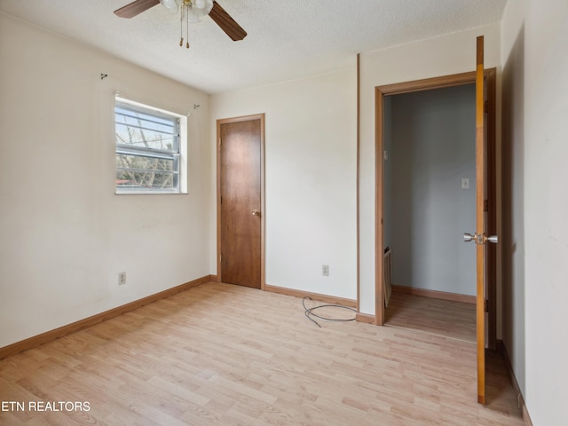 unfurnished bedroom with a textured ceiling, light wood-type flooring, and baseboards