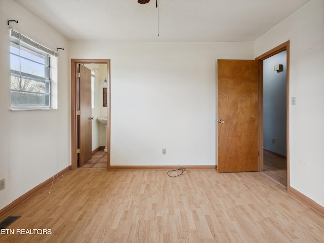 spare room with ceiling fan, wood finished floors, visible vents, and baseboards