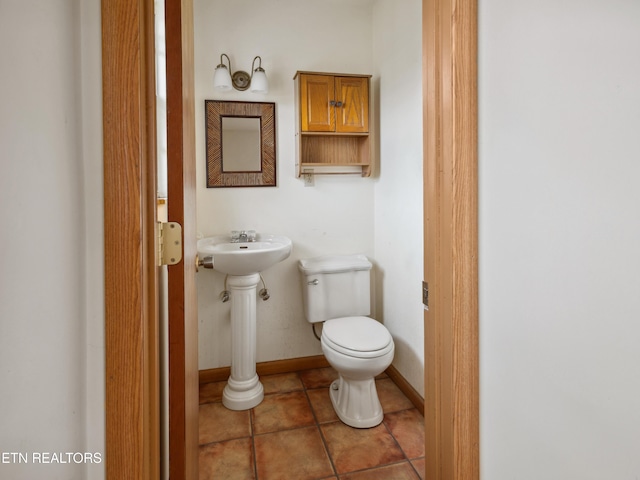 half bath featuring baseboards, toilet, and tile patterned flooring