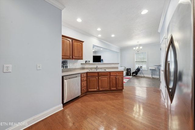 kitchen with brown cabinets, light countertops, appliances with stainless steel finishes, ornamental molding, and hardwood / wood-style floors