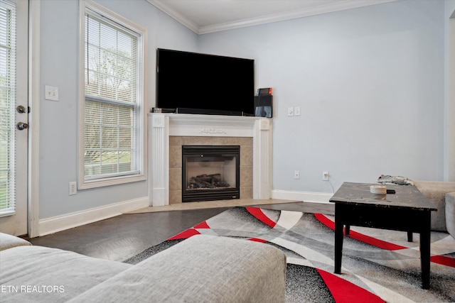 living area with a tile fireplace, crown molding, and baseboards