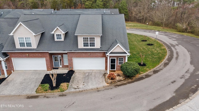 view of front of house with a garage, driveway, roof with shingles, and brick siding