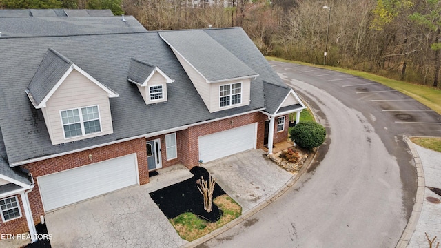 view of front of home featuring a garage, driveway, a shingled roof, and brick siding