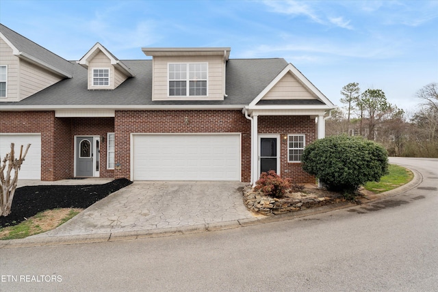 view of front of house with a garage, driveway, brick siding, and a shingled roof