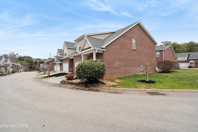 view of property exterior featuring driveway, a residential view, a lawn, and brick siding