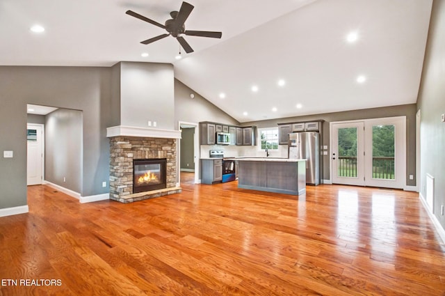 unfurnished living room with light wood-style floors, a sink, a fireplace, and baseboards