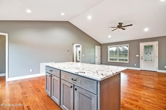 kitchen with lofted ceiling, light wood-type flooring, a center island, and gray cabinetry