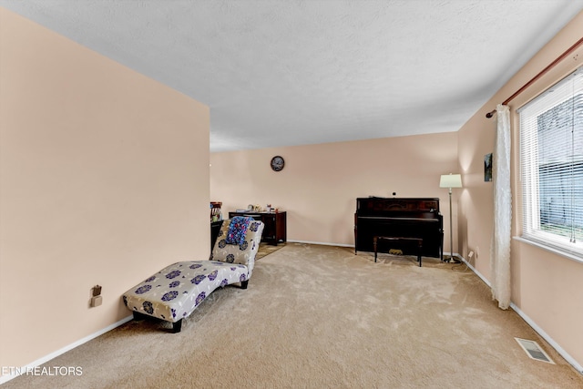 living area featuring a textured ceiling, carpet floors, visible vents, and baseboards