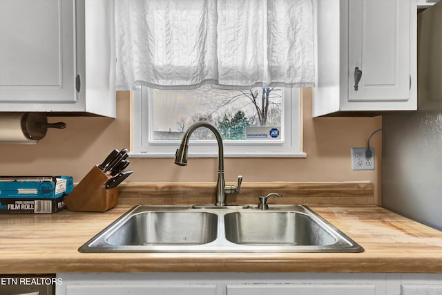 room details featuring stainless steel dishwasher, white cabinets, and a sink