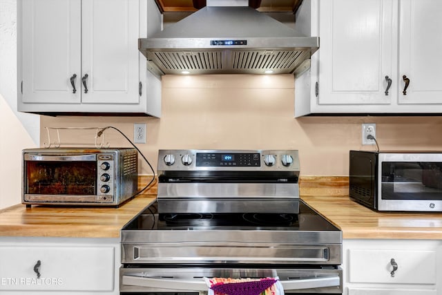 kitchen with extractor fan, a toaster, stainless steel appliances, butcher block counters, and white cabinets