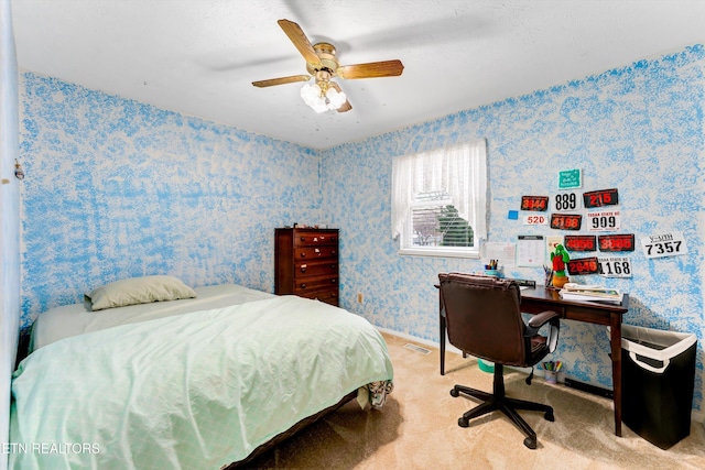 carpeted bedroom with wallpapered walls, visible vents, and a ceiling fan