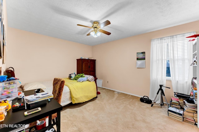 bedroom with a textured ceiling, baseboards, a ceiling fan, and light colored carpet