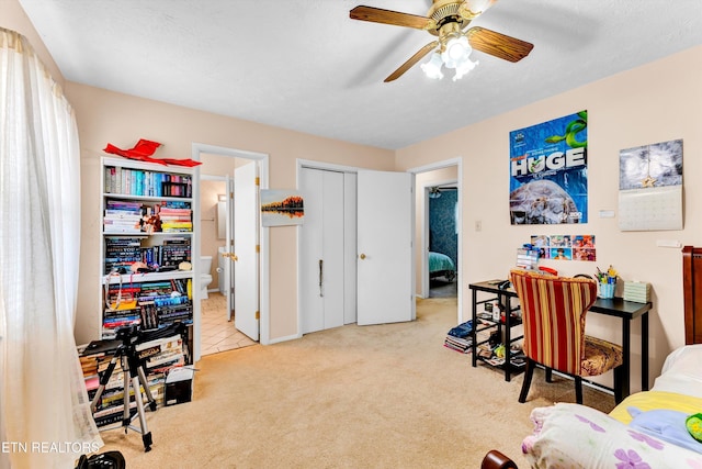 carpeted bedroom featuring ensuite bath, a textured ceiling, a ceiling fan, and a closet