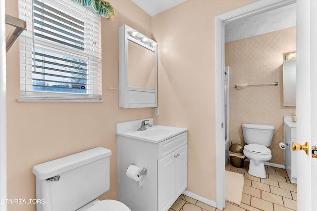 bathroom featuring toilet, tile patterned flooring, baseboards, and vanity