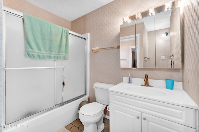 bathroom with combined bath / shower with glass door, vanity, toilet, and wallpapered walls