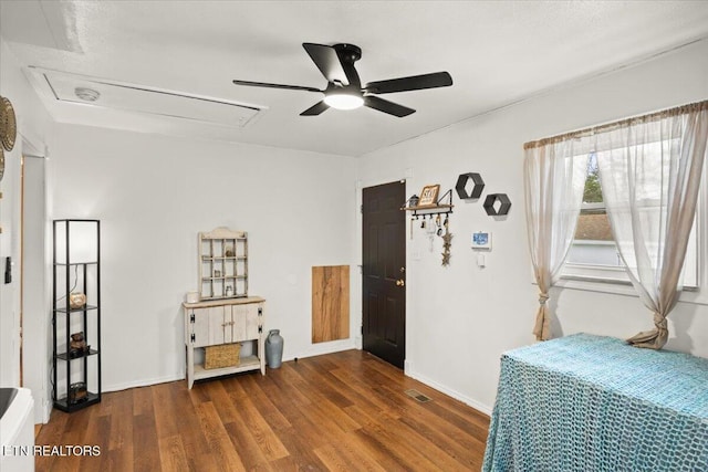 interior space featuring ceiling fan, wood finished floors, visible vents, baseboards, and attic access