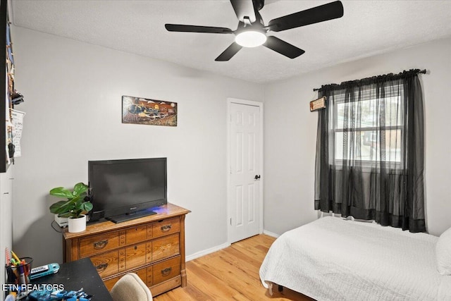 bedroom featuring baseboards, ceiling fan, a textured ceiling, and light wood-style floors