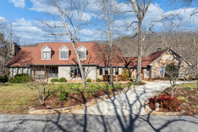 view of front of house featuring concrete driveway, a front lawn, and stone siding