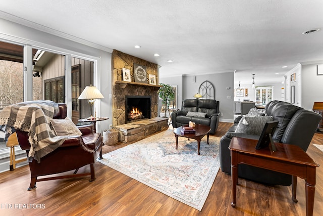 living room with crown molding, recessed lighting, a fireplace, wood finished floors, and a textured ceiling