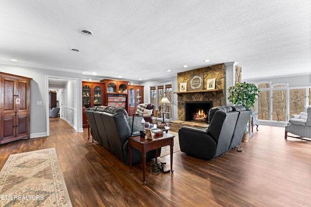 living room with dark wood-style floors, visible vents, a fireplace, and a textured ceiling