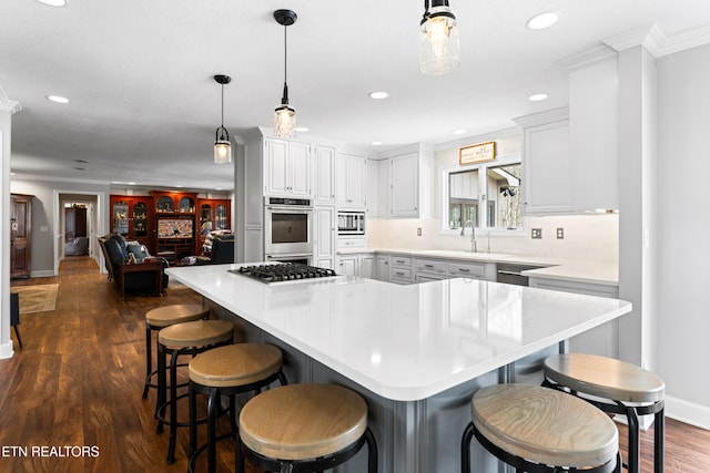 kitchen featuring a large island, a sink, dark wood finished floors, appliances with stainless steel finishes, and light countertops