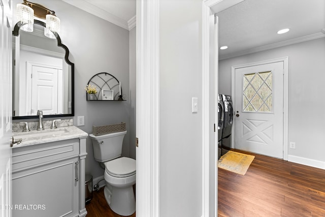 bathroom featuring toilet, independent washer and dryer, ornamental molding, wood finished floors, and vanity