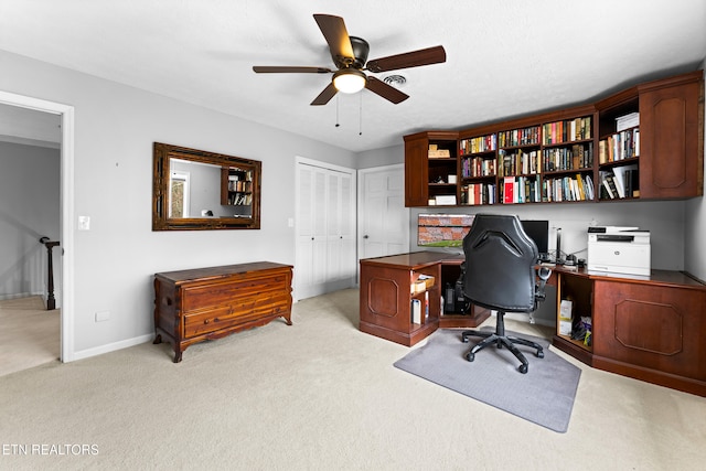 home office featuring a ceiling fan, baseboards, and light carpet