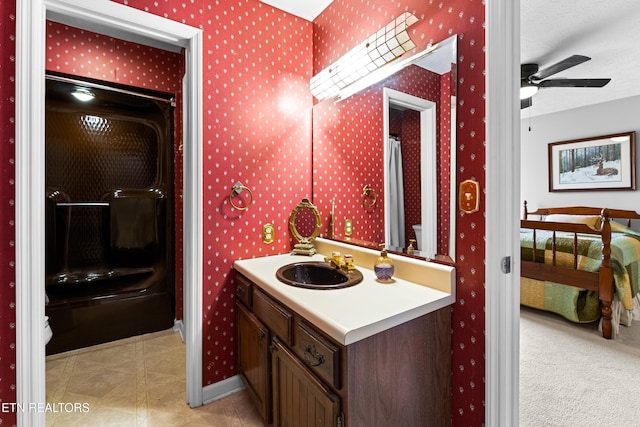 full bath featuring connected bathroom, wallpapered walls, baseboards, vanity, and a textured ceiling