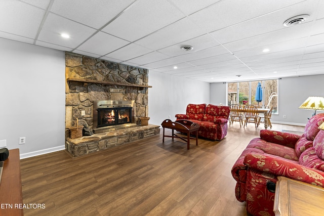 living room featuring visible vents, a paneled ceiling, wood finished floors, and a fireplace