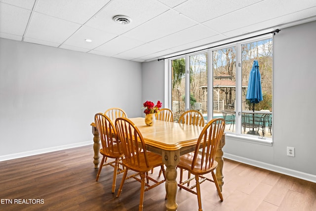 dining space with wood finished floors, visible vents, a wealth of natural light, and baseboards