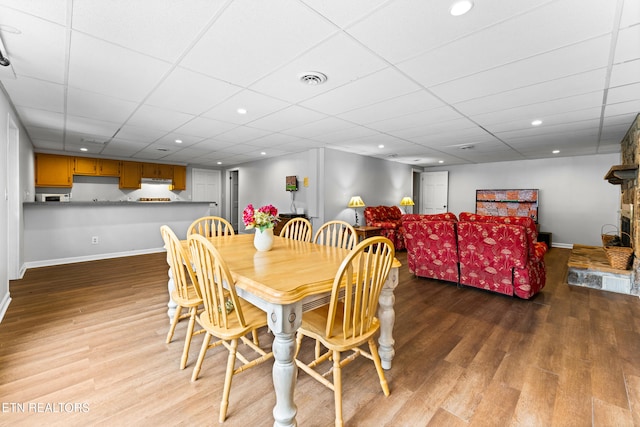 dining room featuring visible vents, a drop ceiling, baseboards, and wood finished floors