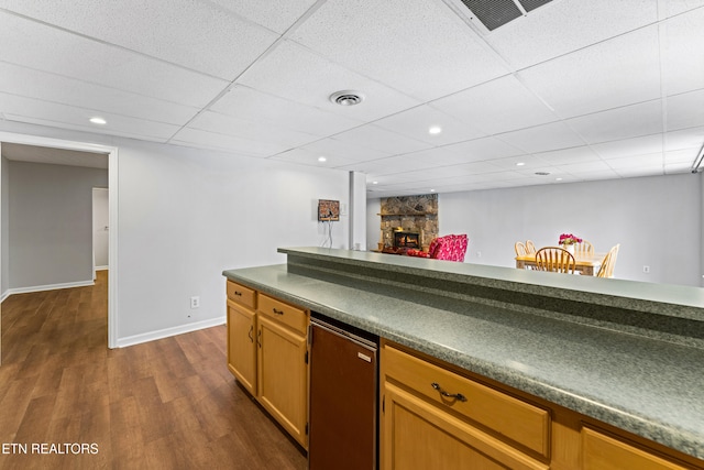 kitchen with visible vents, dark wood-type flooring, dark countertops, fridge, and a fireplace