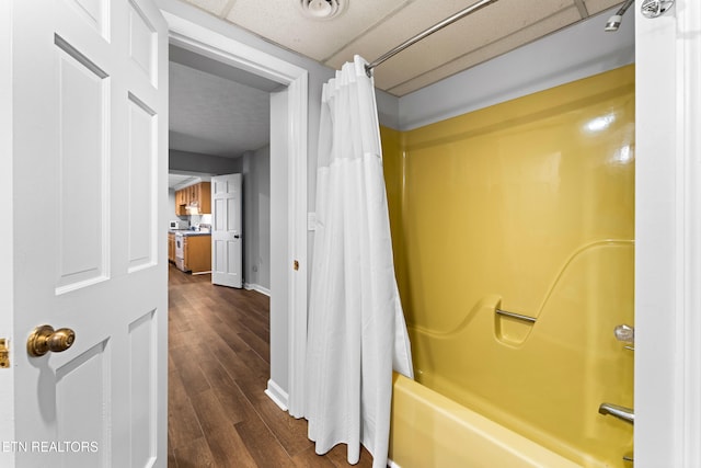 bathroom with shower / tub combo, baseboards, and wood finished floors