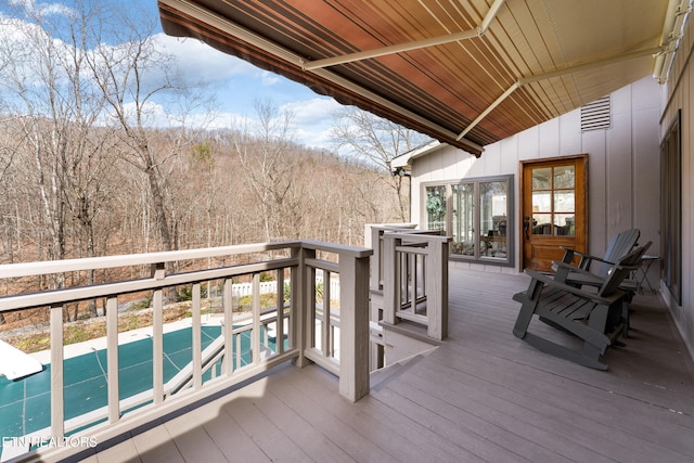 deck featuring shuffleboard and a wooded view