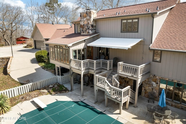 rear view of house featuring stairway, a wooden deck, roof with shingles, a chimney, and a sunroom