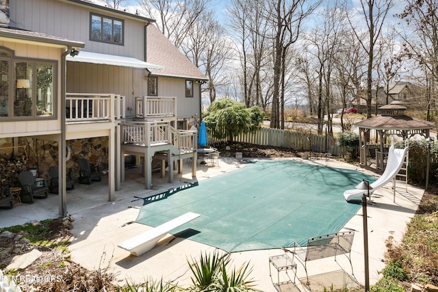 view of swimming pool with a patio, fence, a fenced in pool, a water slide, and a gazebo