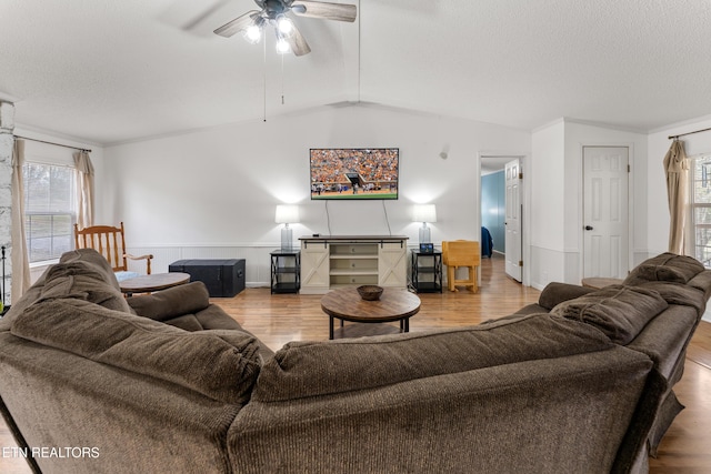 living area featuring wood finished floors, a textured ceiling, lofted ceiling, and ceiling fan