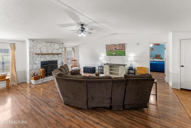 living area with dark wood finished floors, a wainscoted wall, a ceiling fan, and vaulted ceiling