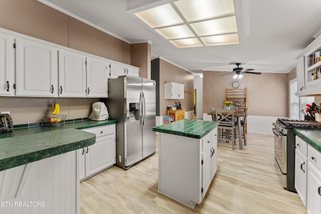 kitchen with a center island, ceiling fan, appliances with stainless steel finishes, light wood-style floors, and white cabinets