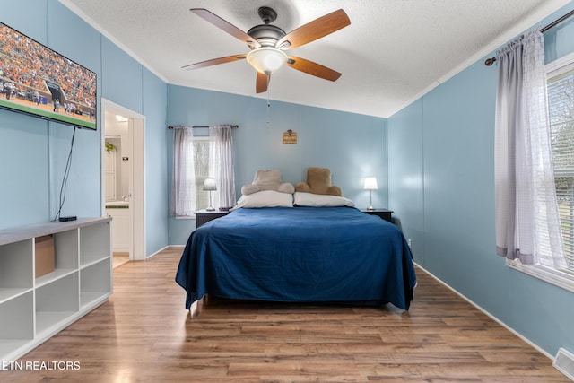 bedroom with multiple windows, wood finished floors, and ornamental molding
