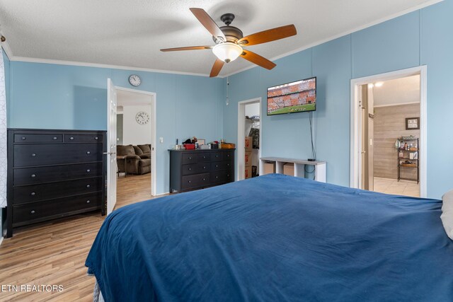 bedroom featuring ensuite bath, light wood-style flooring, a spacious closet, and ornamental molding