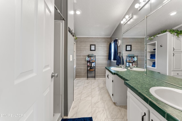 full bathroom with a sink, marble finish floor, a textured ceiling, and ornamental molding