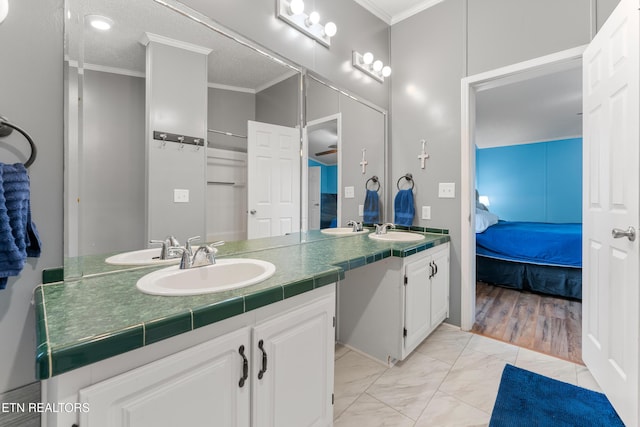 ensuite bathroom featuring marble finish floor, connected bathroom, crown molding, and a sink