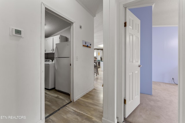 hallway with ornamental molding, light wood-style floors, and a textured ceiling