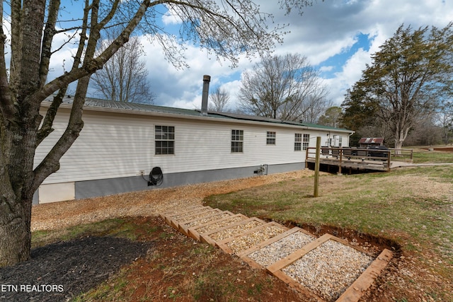 back of property with a deck, a yard, and metal roof