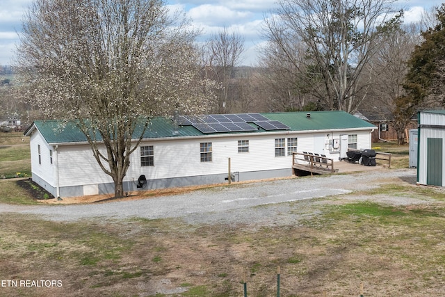 rear view of property featuring crawl space, roof mounted solar panels, and metal roof