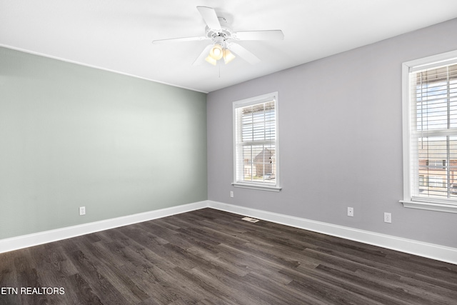 empty room with baseboards, dark wood-type flooring, and a healthy amount of sunlight