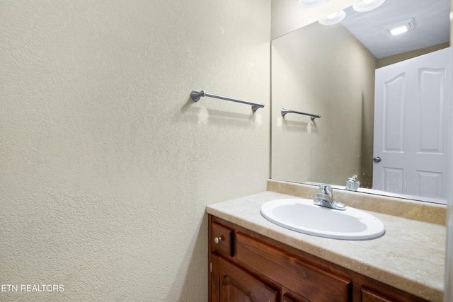 bathroom featuring a textured wall and vanity