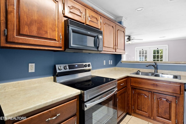 kitchen with light tile patterned floors, light countertops, stainless steel range with electric stovetop, black microwave, and a sink