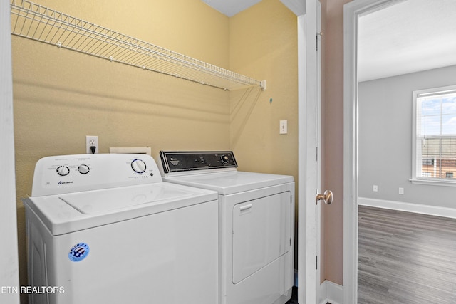 washroom featuring laundry area, baseboards, washing machine and clothes dryer, and wood finished floors